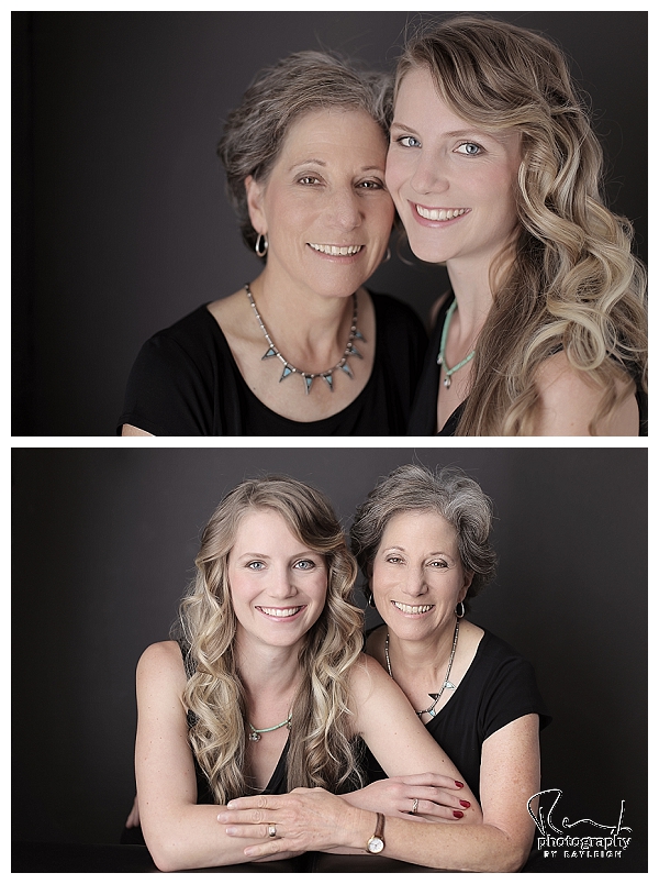 Mother-Daughter session. This image is of an older woman and her grown daughter, standing in front of a black background wearing black tops. Photography by Rayleigh. For more info, visit byrayleigh.com