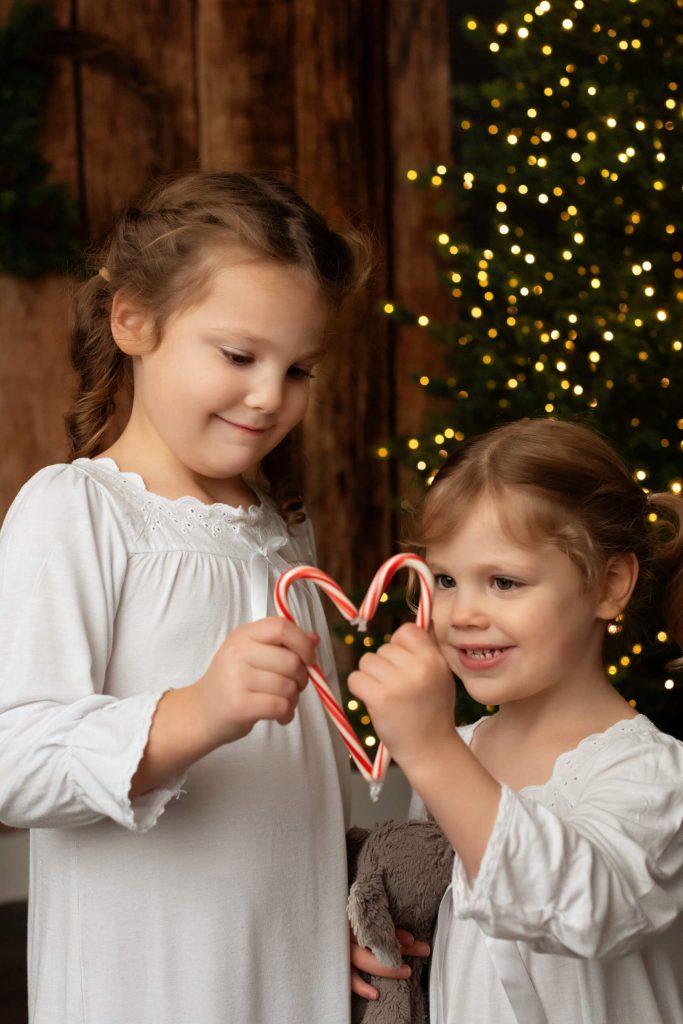 Santa Sessions in Portland, Oregon. Experience the magic of Christmas. These children are holding candy canes to form a heart during their photo shoot.