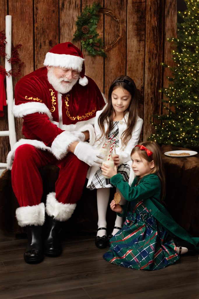 Santa Sessions in Portland, Oregon. Experience the magic of Christmas. Santa is having milk and cookies with the children during the photoshoot.