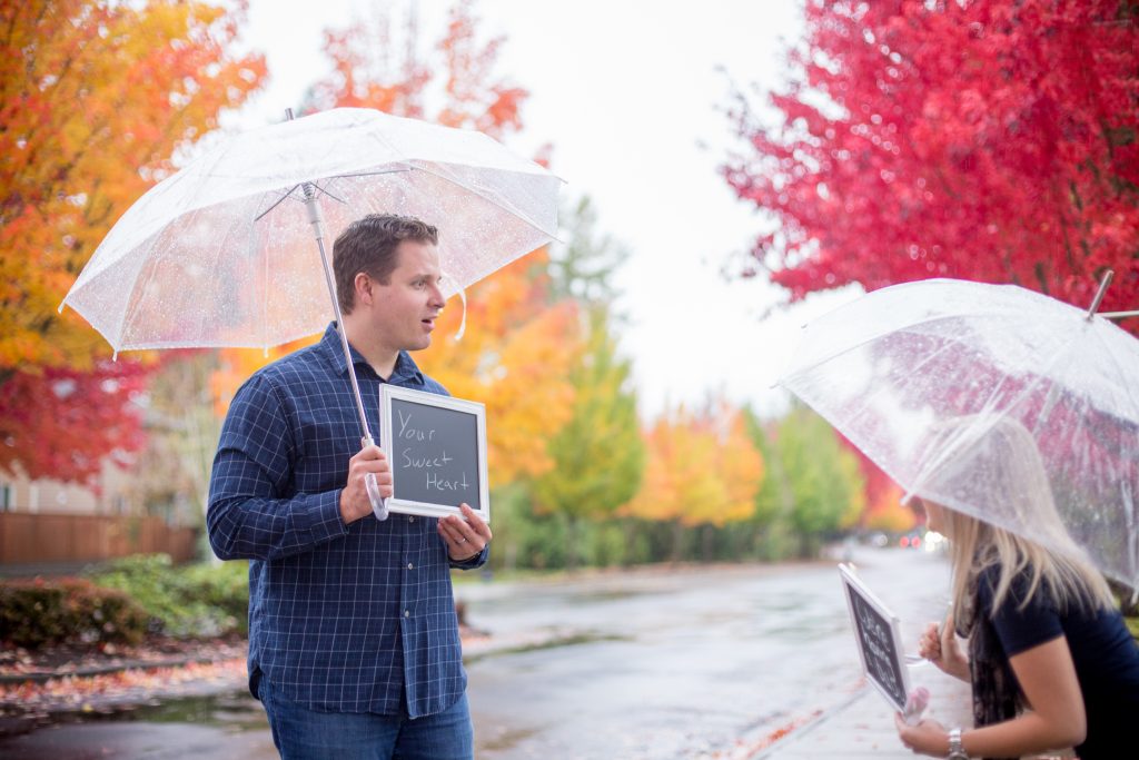 Pregnancy Announcement Idea: A Fall rainy day photo shoot. A pregnant woman is surprising her husband and letting him know his he going to be a Dad. They used chalkboards while holding umbrellas. For more info about maternity portraits, visit byRayleigh.com Photography by Rayleigh