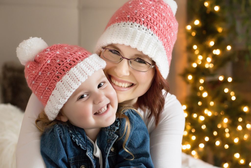 What to wear for a winter photo shoot in Portland. This is an image of a young girl and her Mom wearing matching Christmas hats. Photography by Rayleigh. byRayleigh.com
