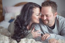 A studio couples engagement photo shoot in Portland, OR. This is a boudoir type pose lying on the bed.