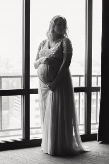 A backlit, full body maternity photo taken in a hotel room in Seattle, WA.