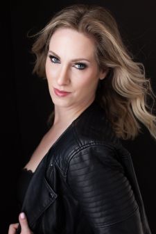 A beauty photo shoot in a studio in Portland, OR. This is a standing pose against a black backdrop.