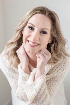 A beauty photo shoot in a studio in Portland, OR. She's in a sitting pose against a white backdrop.
