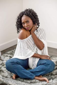 A boudoir photo shoot in a studio in Portland, OR. This is a beautiful black woman sitting on the floor in a boudoir pose.