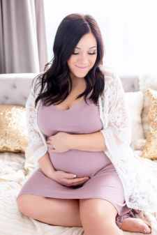 a studio boudoir maternity photo taken in Portland, OR. This is a sitting on the bed pose.