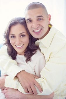 A studio engagement couples photo shoot in Portland, OR. This is a backlit photo with the couple sitting on a sofa.