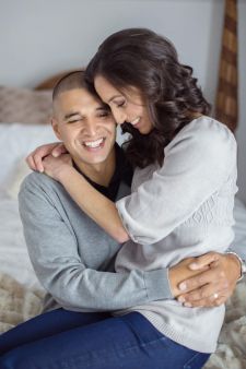 A studio couples engagement photo shoot in Portland, OR. This is a boudoir type pose sitting on the bed.