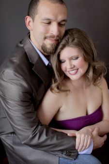 A studio couples engagement photo shoot in Portland, OR. This is a sitting on the floor pose with a black background.