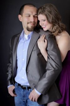 A studio couples engagement photo shoot in Portland, OR. This is a standing pose with a black background.