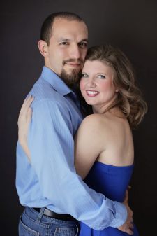 A studio couples engagement photo shoot in Portland, OR. This is a standing pose with a black background.