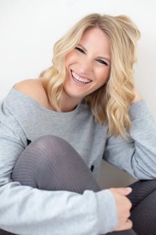A beauty photo shoot in a studio in Portland, OR. This is a sitting pose and she is laughing.
