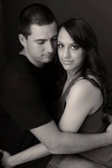 A studio couples photo shoot in Portland, OR. This is a sitting on the floor pose with a black background.