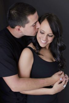 A studio couples photo shoot in Portland, OR. This is a sitting on the floor pose with a black background.