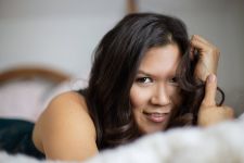 A boudoir photo shoot in a studio in Portland, OR. She is lying on a bed.