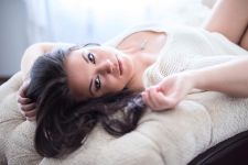 A boudoir photo shoot in a studio in Portland, OR. She is lying on a chase in a boudoir pose.