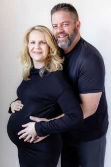 a studio couples maternity photo taken in Portland, OR. This is a standing pose against a white backdrop.