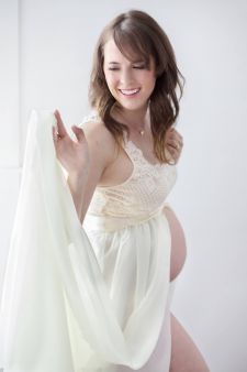 a studio boudoir maternity photo taken in Portland, OR. This is a standing pose against a white backdrop.