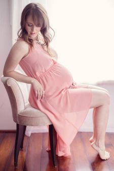 a studio maternity photo taken in Portland, OR. This is a sitting pose in front of a window.