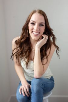 A beauty photo shoot in a studio in Portland, OR. This is a sitting pose against a white wall.