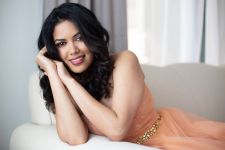 A beauty photo shoot in a studio in Portland, OR with an Indian woman. This is a sitting pose on a sofa in a formal gown.
