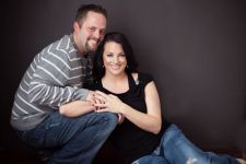 A studio couples engagement photo shoot in Portland, OR. This is a sitting on the floor pose with a black background.