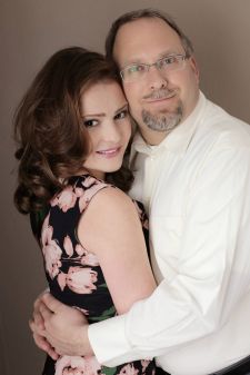 A studio couples photo shoot in Portland, OR. This is a standing pose with a brown background.