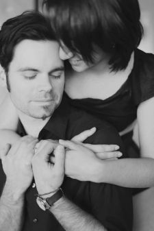 A studio couples photo shoot in Portland, OR. This is a boudoir type pose sitting on the bed.