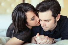 A studio couples photo shoot in Portland, OR. This is a boudoir type pose lying on the bed.