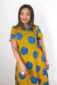 A beauty photo shoot in a studio in Portland, OR. She is wearing an African dress and in a standing pose against a white backdrop.