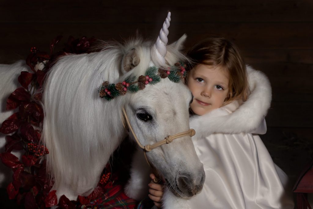 Unicorn Christmas mini sessions near Portland, OR. Stylized fine art portraits that are dark and moody with light effects. This girl is wearing a white winter cloak.