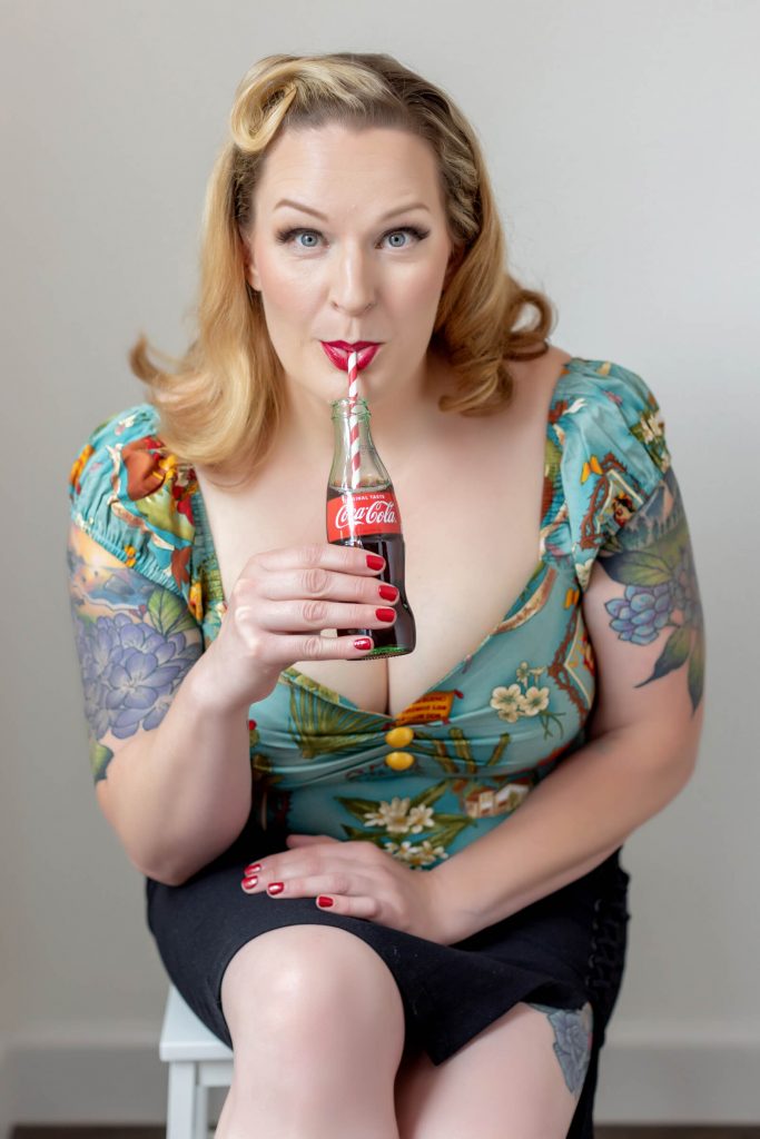 A posed studio image from a pin up photo shoot experience in Portland. Props include a vintage looking bottle of Coca-Cola.