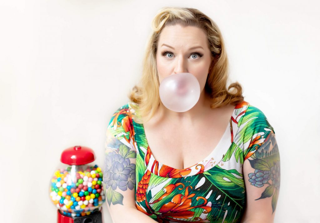 A posed studio image from a pin up photo shoot experience in Portland. Props include a gumball machine and bubble gum.