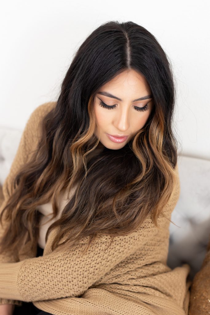 A Fall beauty photo shoot in Portland, Oregon by beauty and boudoir photographer, Photography by Rayleigh. This is an image of a women sitting on a bed, wearing a brown sweater and Fall wardrobe.