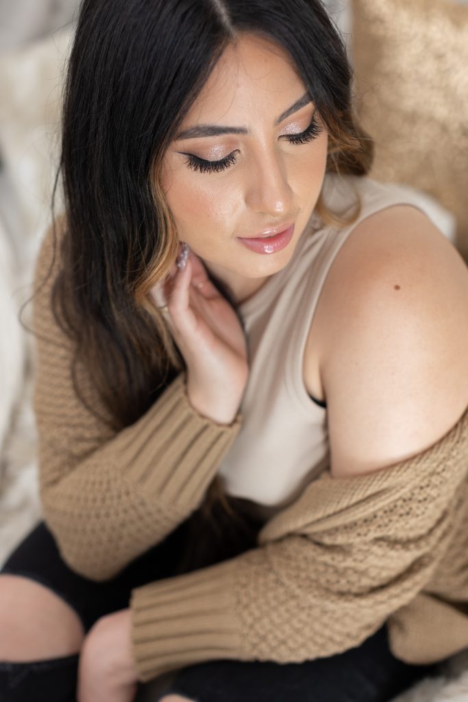 A Fall beauty photo shoot in Portland, Oregon by beauty and boudoir photographer, Photography by Rayleigh. This is a modest boudoir image of a women sitting on a bed, wearing a brown sweater and Fall wardrobe.